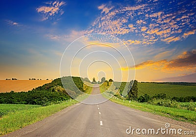 Sunrise over picturesque landscape. Straight road and fields Stock Photo