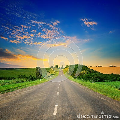 Sunrise over picturesque landscape. Straight road and fields Stock Photo