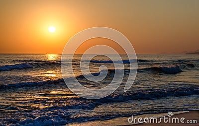 Sunrise over the sea, the rolling calm waves, sandy beach Stock Photo