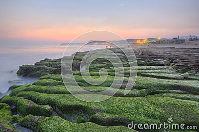 Sunrise by a peculiar rocky beach with dramatic dawning sky Stock Photo