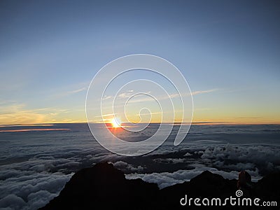 Sunrise at the top of Mount Rinjani in Lombok Island, Indonesia. View of crater lake covered in clouds from the summit. Beautiful Stock Photo