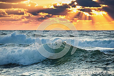 Sunrise Wave. Colorful ocean beach sunrise with deep blue sky and sun rays. Stock Photo