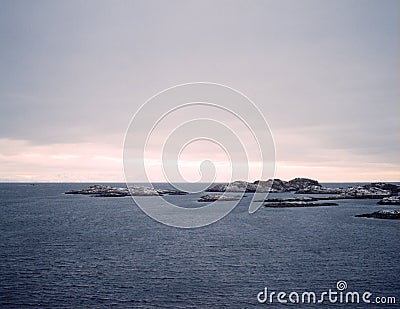 Sunrise, winter, unfrozen water, snow-capped mountains and reflection of the pink sky, Stock Photo