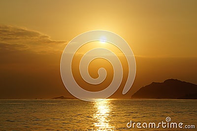 Sunrises in between Kaohikaipu (Black/Turtle) Island and Makapuu with sunlight reflecting on the ocean water of Waimanalo bay Stock Photo