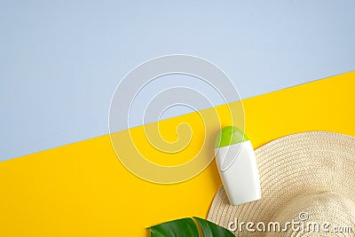 Sunscreen cream bottle mockup on yellow and blue background with tropical leaf and female hat. Sun protection and beach skin care Stock Photo