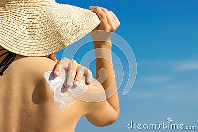 Sunscreen sunblock. Woman in a hat putting solar cream on shoulder outdoors under sunshine on beautiful summer day Stock Photo