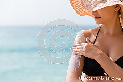 Sunscreen sunblock. Woman in a hat putting solar cream on shoulder outdoors under sunshine on beautiful summer day Stock Photo