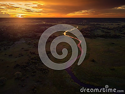 Sunset, aerial, atmospheric view on curving river Khwai, Moremi forest, Botswana. Typical ecosystem, part of Okavango delta, Stock Photo