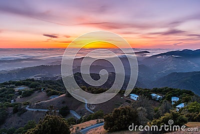 Sunset afterglow over a sea of clouds; winding road descending through rolling hills in the foreground; Mt Hamilton, San Jose, Stock Photo