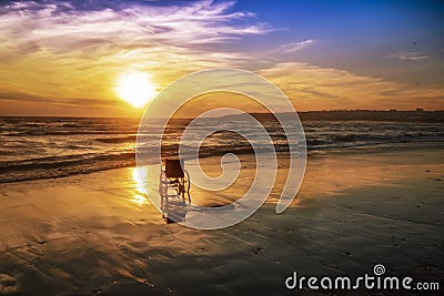 Sunset on the beach handicapped wheelchair Stock Photo