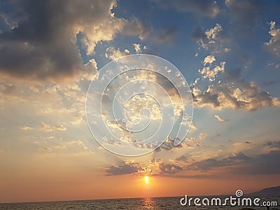 sunset beams clouds sun blue and orange golden colors greece Stock Photo