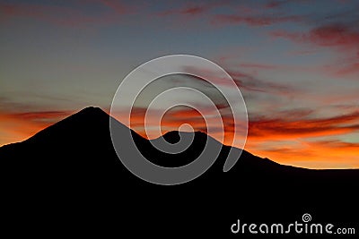 Sunset behind the volcano mountain silhouette Stock Photo