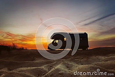 Camper van parked next to beach. Sunset in the background. Summer traveling concept. Stock Photo