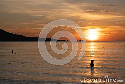 Sunset casting warm hues on rippling water, as seagulls soar in the sky Stock Photo