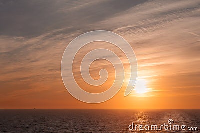 Sunset and colorful sky on the sea with a wake left by a cruise ship Stock Photo