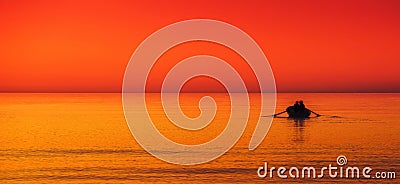 little boat in a sea red orange sky at sunset Stock Photo