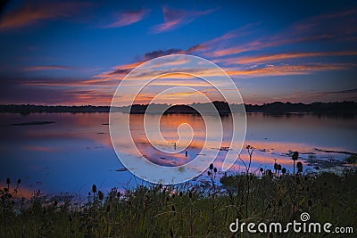 Sunset colours illuminate clouds reflected perfectly in Poole Ha Stock Photo