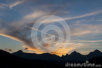 Sunset and contrail over mountains Stock Photo