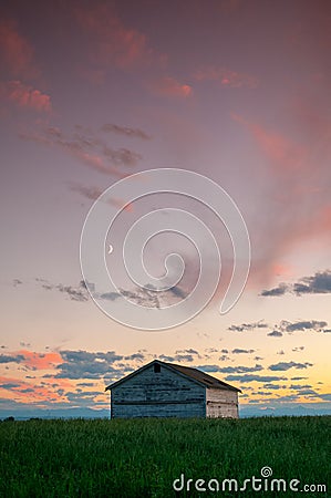 Sunset and a couple abandoned and broken down farm house in the Alberta prairies Stock Photo