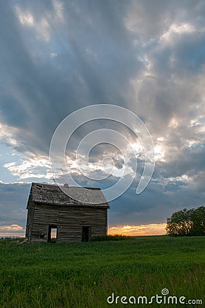 Sunset and a couple abandoned and broken down farm house in the Alberta prairies Stock Photo
