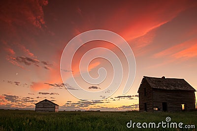 Sunset and a couple abandoned and broken down farm house in the Alberta prairies Stock Photo