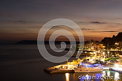 Sunset in croatian resort Podgora, last beams of sun and colorful city illumination. Stock Photo