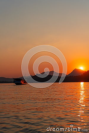 Sunset cruise in luang prabang on the mekong river. Sky is on fire as the sun hitting the mountains. Stock Photo