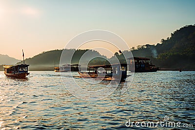 Sunset cruise in luang prabang on the mekong river. Soft light hit the boats in the water. Most of them are on a sunset cruise. Editorial Stock Photo