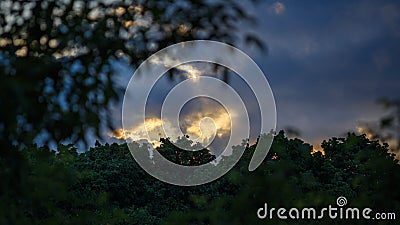 Sunset in deep clouds over trees horizon Stock Photo