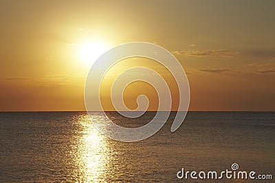 Sunset on the flat sea. Light orange reflection on the waves Stock Photo