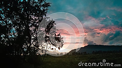 sunset at the foot of the mountains with shady trees Stock Photo