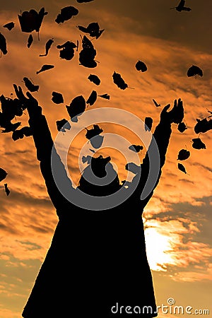 Sunset of girl throwing leaves in the air Stock Photo