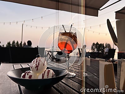Sunset Glass of strawberry water with ice and icecream on woodentable at beach restoran view from glass door modern architecture Stock Photo