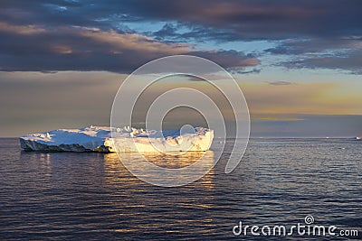 Sunset with shiny iceberg, reflecting in Arctic Ocean Iceberg, Greenland Stock Photo