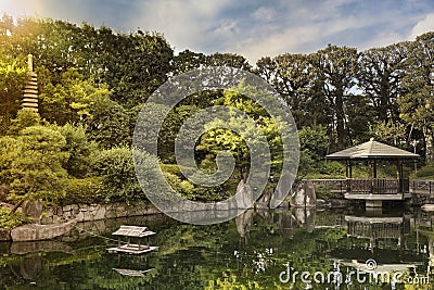 Sunset on hexagonal Gazebo Ukimido in the central pond of Mejiro Garden where ducks are resting and which is surrounded by large Stock Photo