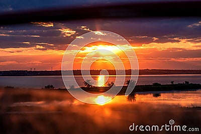 Sunset on the lake. View of the setting sun from the car window. Stock Photo