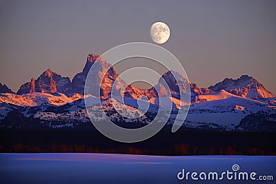 Sunset Light Alpen Glow on Tetons Teton Mountains wtih Moon Rising Stock Photo