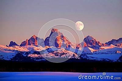 Sunset Light Alpen Glow on Tetons Teton Mountains wtih Moon Rising Stock Photo