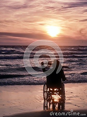 Sunset, makes sightseeing on the beach a woman on wheelchair Stock Photo