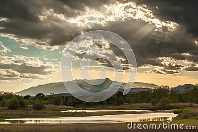 sunset in the mountains with rays of light passing through the valley, thick clouds with rays of light illuminated the lake in Stock Photo