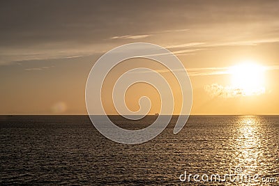 Sunset over Mykonos island, Cyclades, Greece. Lighthouse, orange yellow sky sparkle sea. Vertical Stock Photo