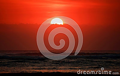 Sunset over the sea. Half the sun behind the clouds, over the horizon. Beach landscape nature pattern background. Stock Photo
