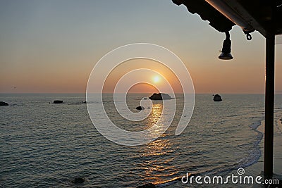 Sunset over the sea at Prasoudi, Corfu seen from the balcony of a tavern Stock Photo