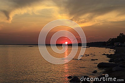 Sunset over the sea. Reflection of the sun in water. Silhouette of paraglider flying in the sky. Sunset beach in a summer evening Stock Photo