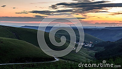 Sunset over the south Wales valleys from the Bwlch mountain. A road winds around the hillside to the village of Abergwynfi. Stock Photo