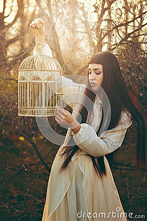 Sunset portrait of young woman with bird cage Stock Photo