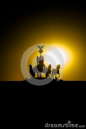 Berlin, Sunset Quadriga at Brandenburg Gate. Silhouette of Quadriga in backlight at sunset with yellow sun ball and orange sky Stock Photo