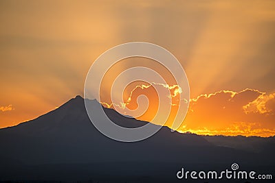 Sunset rays behind silhouette of mountain Stock Photo