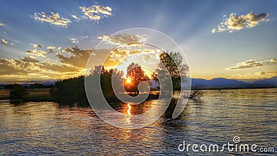 Sunset rays through trees on the lake Stock Photo