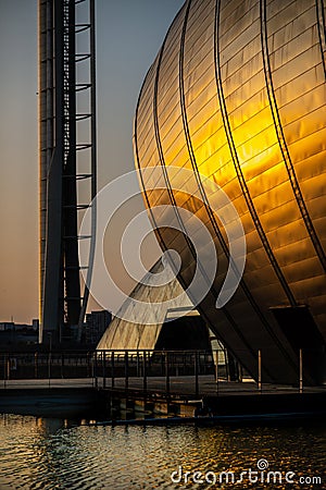 Sunset Reflected on the Curved Exterior of the Science Centre and in Ripples on a Pond in the Foreground in Glasgow Scotland Editorial Stock Photo